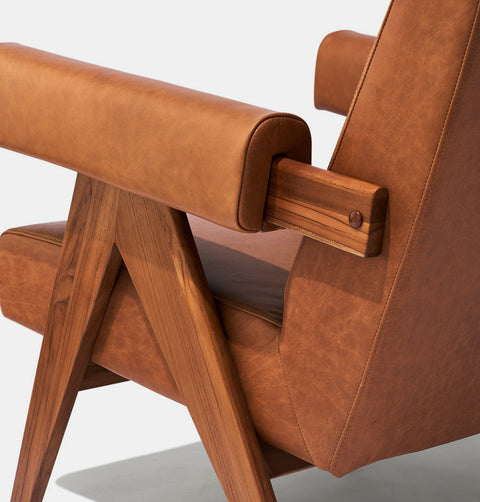 Caramel brown leather lounge chair with leather armrests and solid ash wood legs stained walnut. Armrest detail.