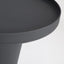 Minimal black powder coated aluminum side table resembling a pier bollard with a black marble base. Top detail.