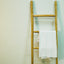 Decorative rustic ladder in natural eucalyptus wood with a towel hanging on one rung.