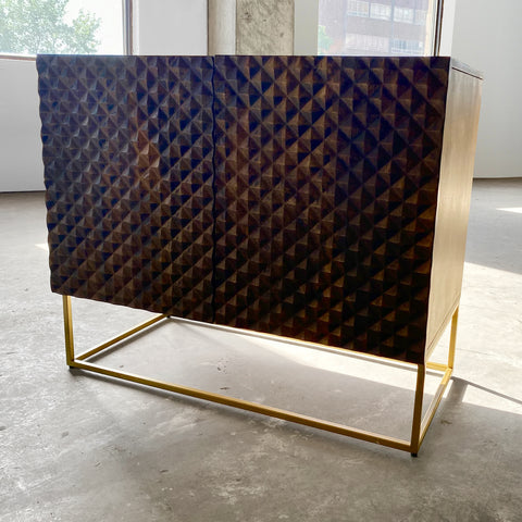 Dark brown mango wood sideboard with a CNC carved repeating pyramid pattern on the two doors. Brass finished iron legs & frame.