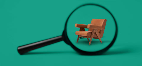 Teal background with magnifying glass in foreground and Nehru lounge chair in view.