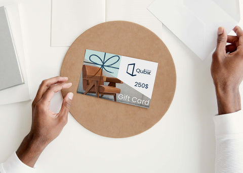 Man's hands at a desk holing an envelope and Qubik Furniture gift card worth a 250$ value.