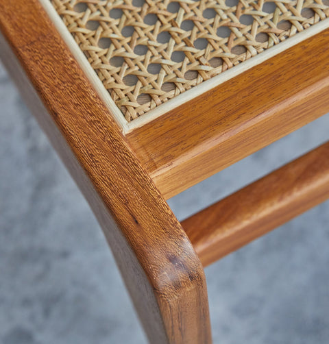 Lounge chair in walnut stained ash wood frame with natural rattan seat and back. Outside corner detail.